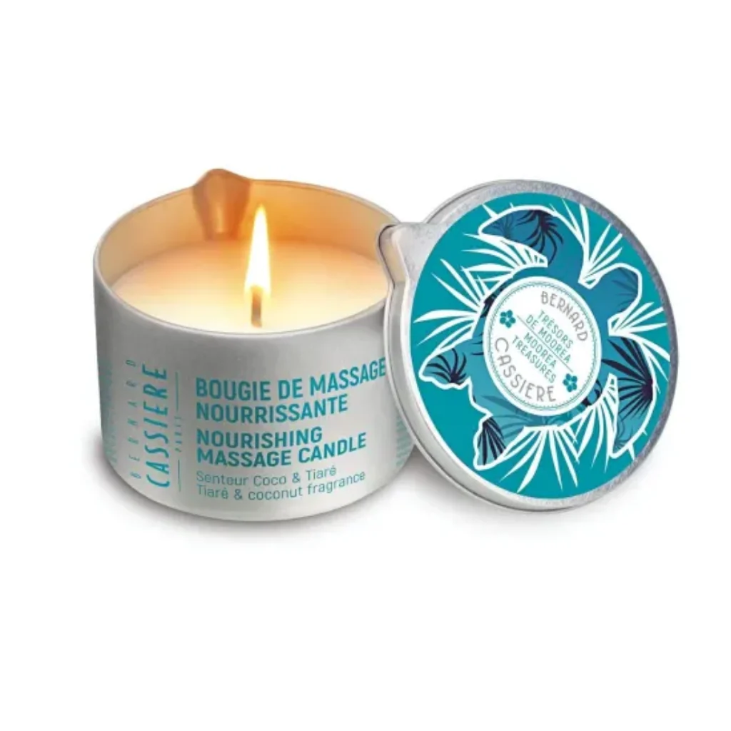 A lit cylindrical massage candle in a silver tin, shown next to its matching lid on a clean white background. The lid features a teal and white tropical leaf pattern.