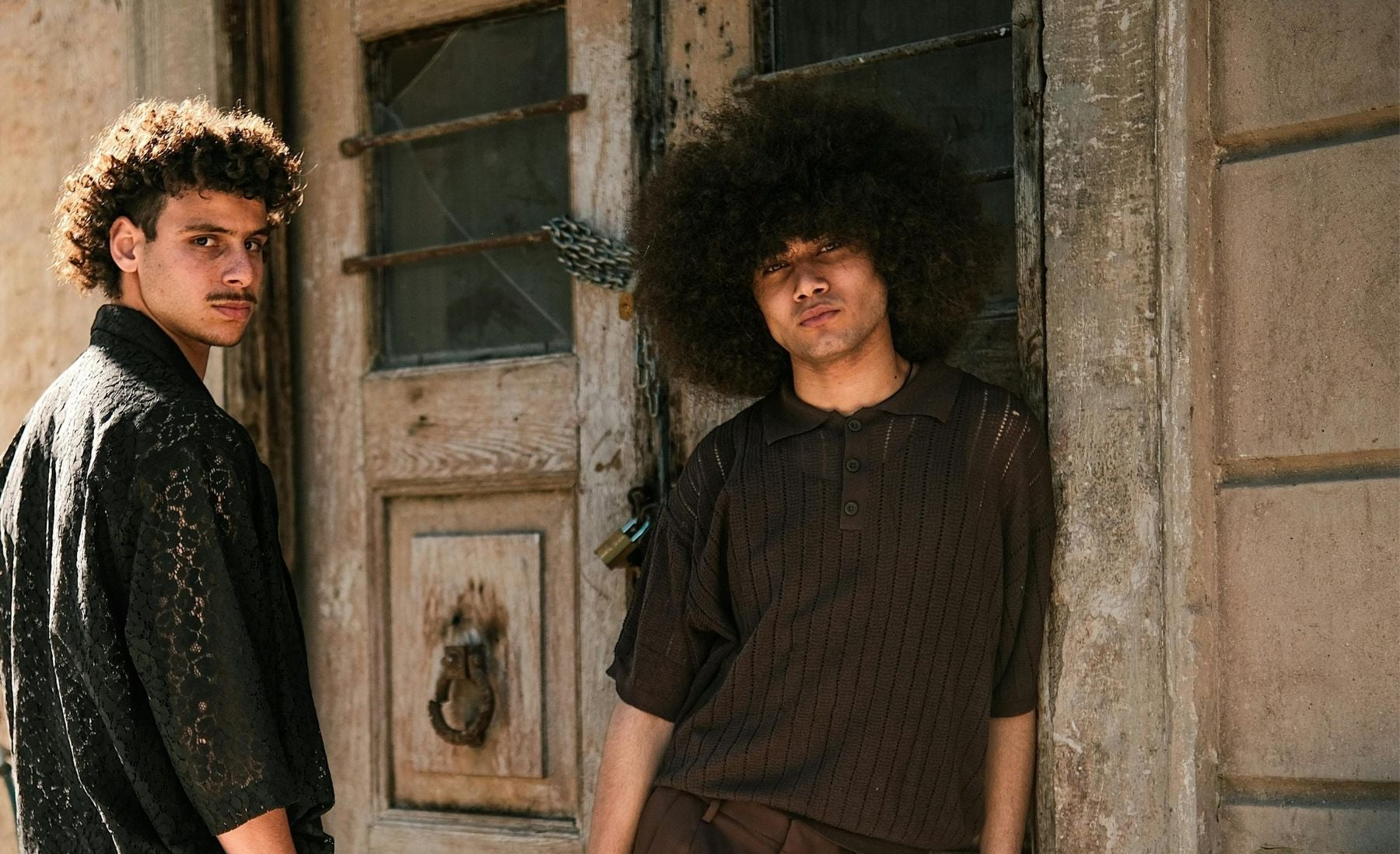 Two men standing in front of a rustic wooden door.