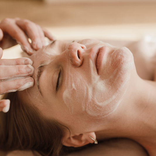 Woman receiving a facial massage with cream on her face